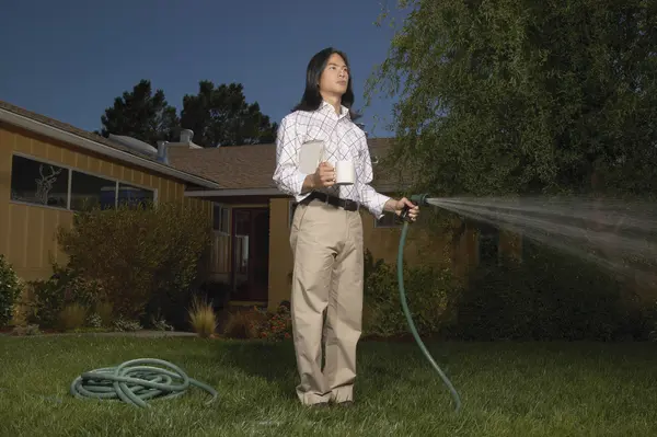 Man with garden hose watering yard