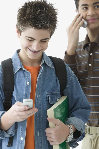 Two teenage boys standing with cell phones