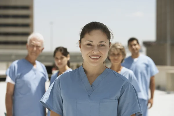 Hispanic female doctor smiling with co-workers in background