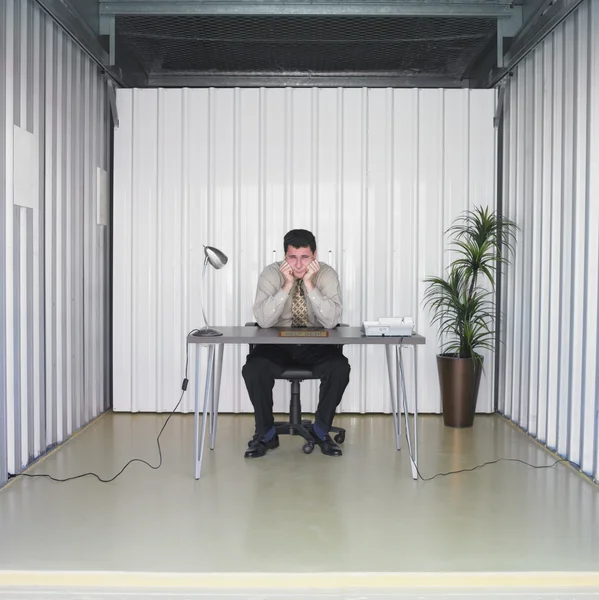 Businessman sitting at desk in storage unit