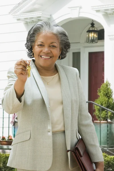 African female real estate agent holding keys to house — Stock Photo #13224387