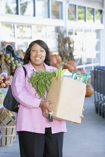 Woman with bag of groceries outside grocery store