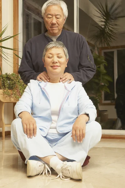Senior Asian man giving senior Asian woman a neck massage