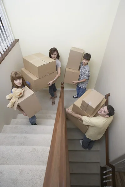 Family carrying moving boxes up stairs