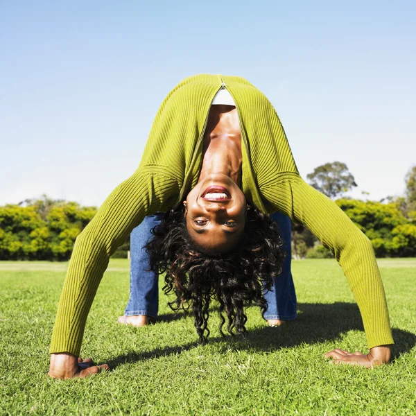 African woman doing back bend in grass