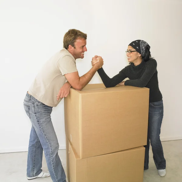 Couple arm wrestling on boxes in new house