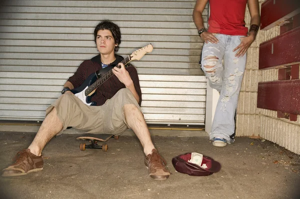 Young man playing guitar for money