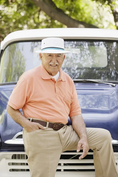 Portrait of elderly man leaning on old pickup truck