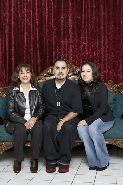 Three Hispanic family members sitting on an antique sofa