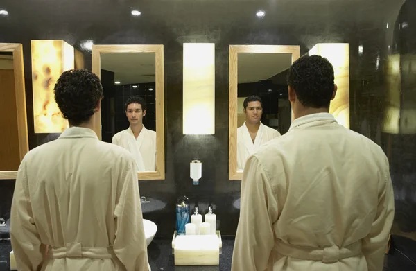 Two men in robes in front of bathroom mirrors