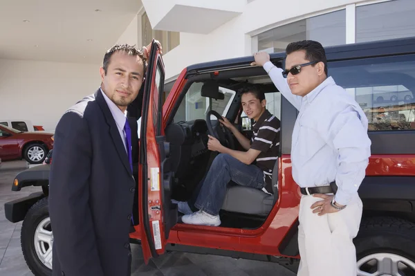 Hispanic father and son at car dealership