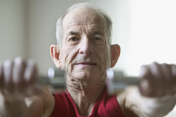 Portrait of elderly man lifting weights