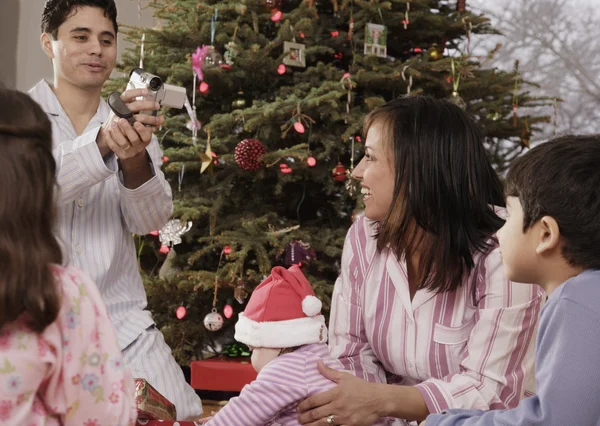 Hispanic father video recording family on Christmas