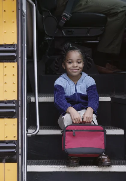 Portrait of girl on school bus steps