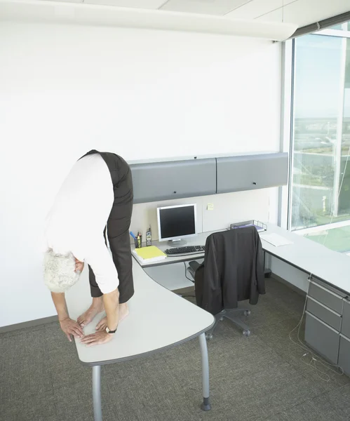 Middle-aged businessman stretching on desk