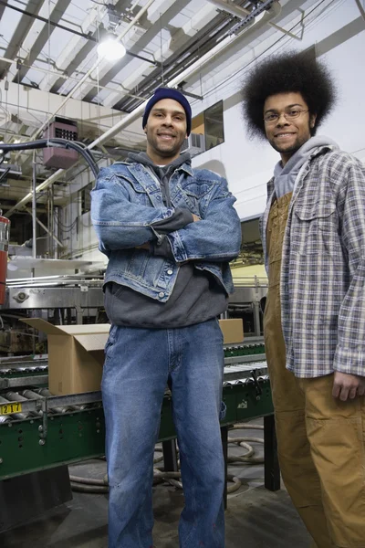 Two men standing in front of conveyor belts
