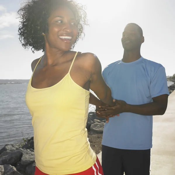 African couple in athletic gear stretching outdoors