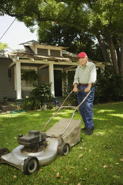 Portrait of elderly man mowing lawn