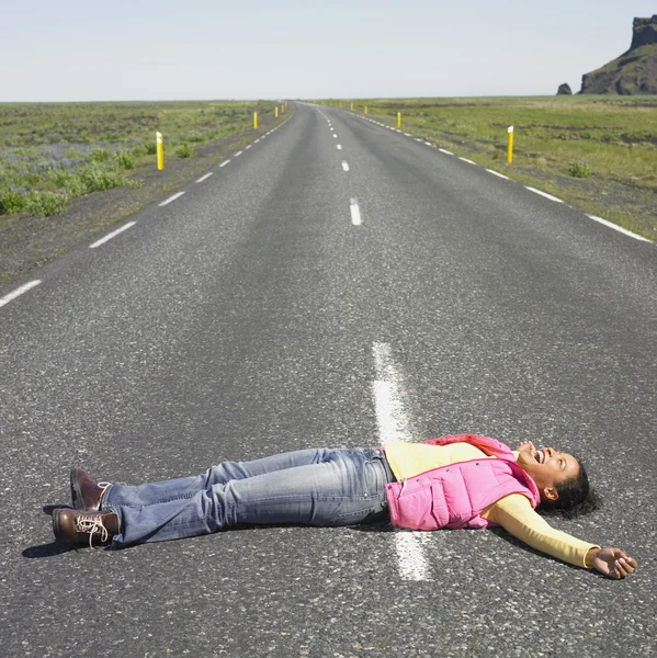 Young woman laying in middle of road laughing