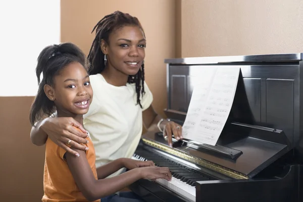 African mother helping daughter with piano lessons