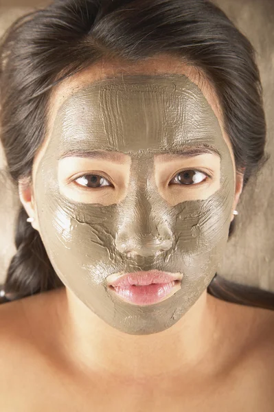 Young woman posing with mud mask facial