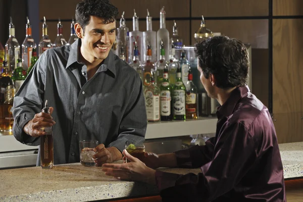 Hispanic male bartender talking to customer