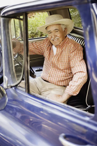 Portrait of elderly man sitting in old pickup truck