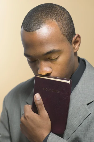 Man with eyes closed kissing Bible