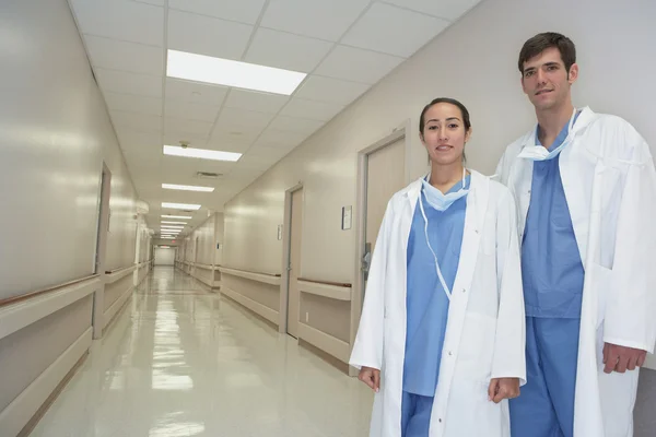 Hispanic female and male doctor standing in hospital corridor