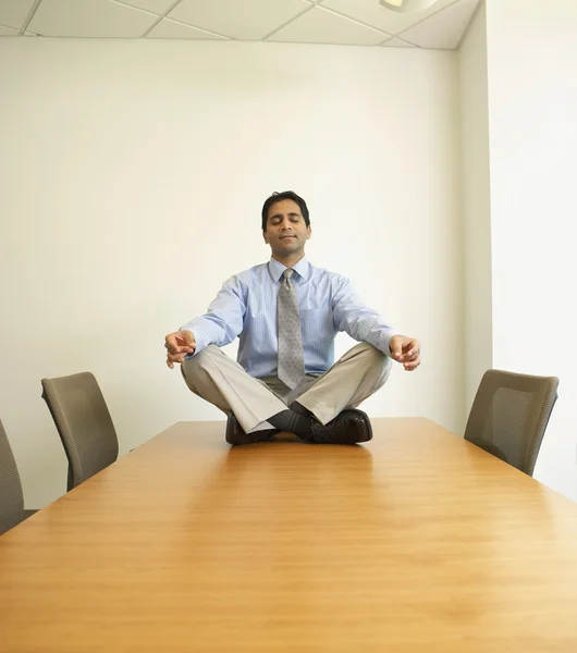 Businessman meditating on conference table
