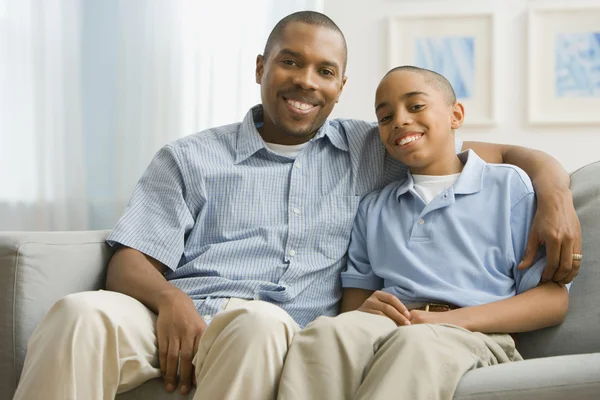 Portrait of African father and son on sofa