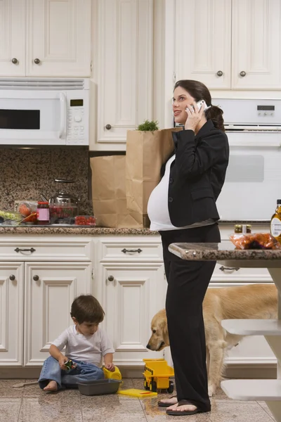 Pregnant Woman on Mobile Phone with Groceries and Toddler