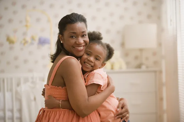 Pregnant African mother hugging young daughter