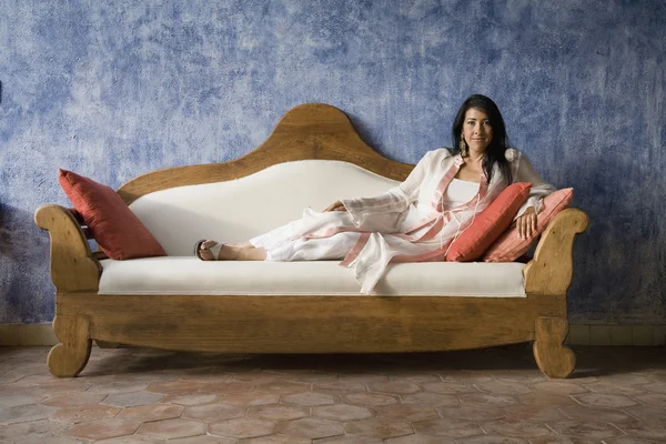 Hispanic woman laying on sofa