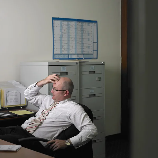 Middle-aged businessman thinking at his desk