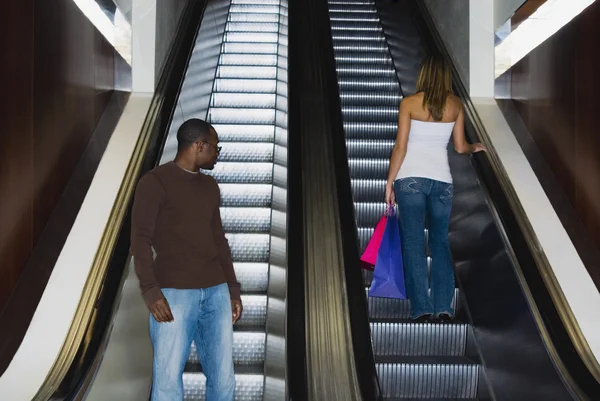 African man looking at woman on escalator