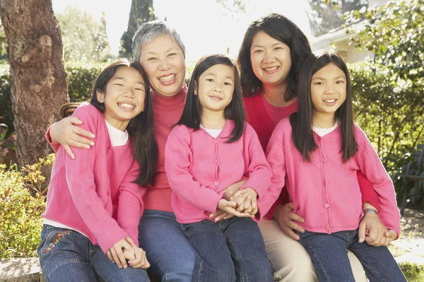 Three generations of female Asian family members smiling outdoors