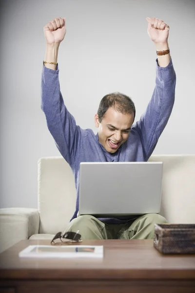 Indian man looking at laptop and cheering