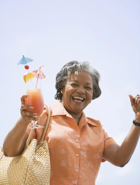 Portrait of senior African woman holding tropical cocktail