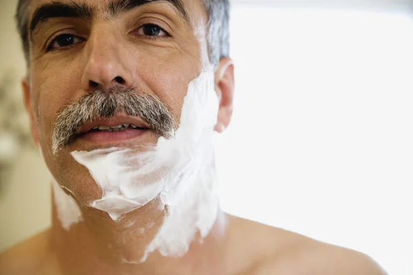 Middle-aged Hispanic man with shaving cream on face