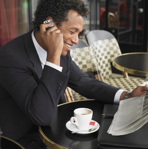 Businessman using cell phone at outdoor cafe