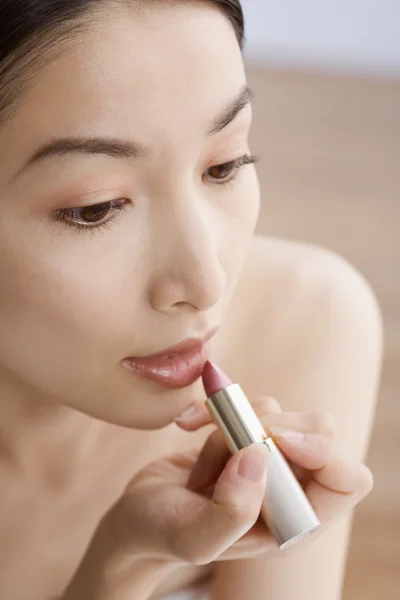 Asian woman applying lipstick