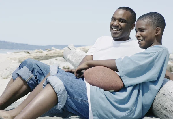 Father and son relaxing at beach with football