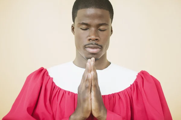 African man praying in church choir gown