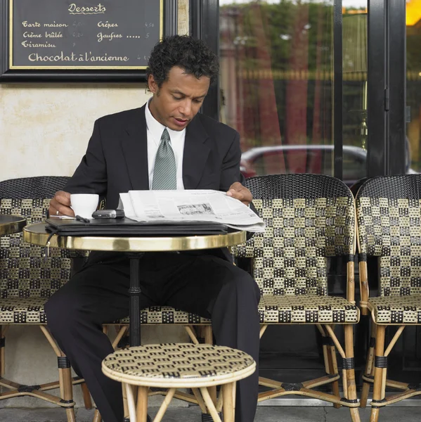 Businessman reading newspaper at outdoor cafe
