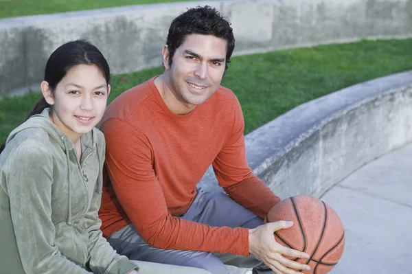 Hispanic father and daughter with basketball