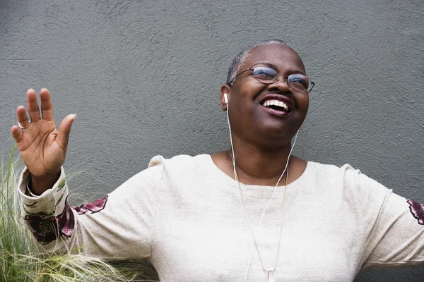 Middle-aged African woman listening to music with earphones
