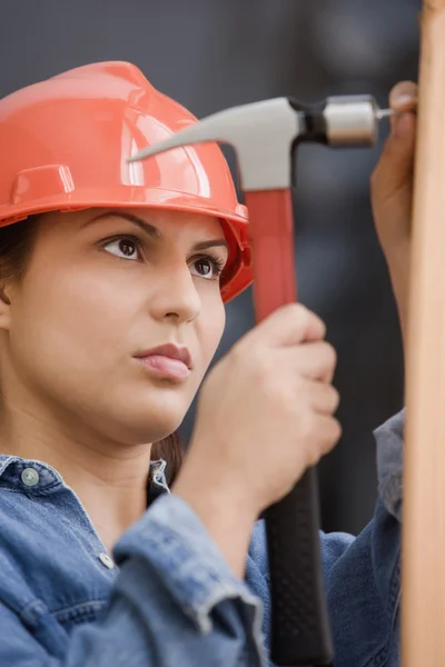 Hispanic female construction worker hammering a nail