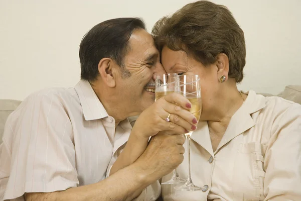 Senior Hispanic couple hugging and toasting with champagne