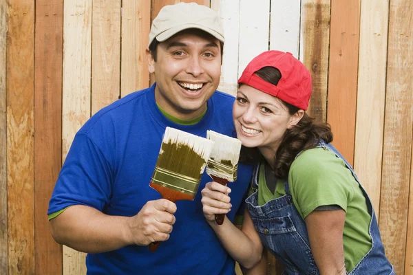 Multi-ethnic couple painting fence — Stock Photo #13235750